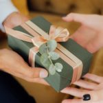 A close-up image of a wrapped gift exchanging hands.