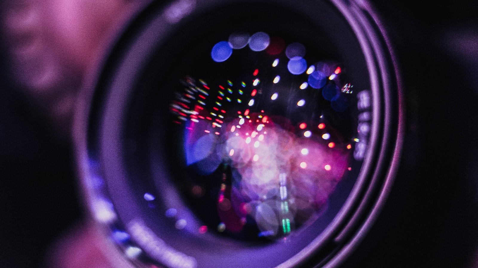 Close-up view of a camera lens focusing on city lights.