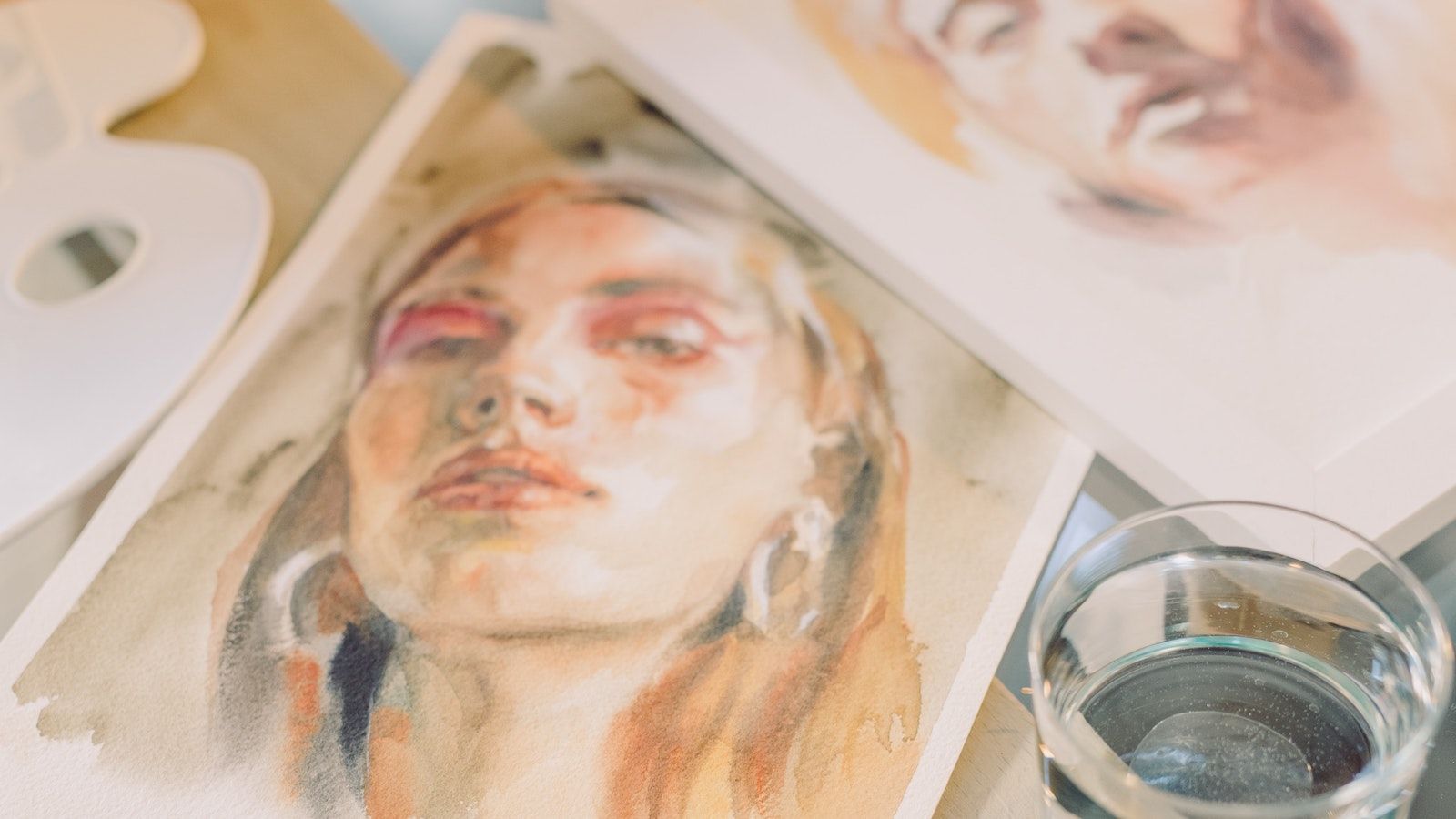 Watercolor portraits in progress laying on a desk.