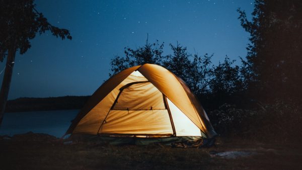 A glowing tent in the wilderness under the stars.